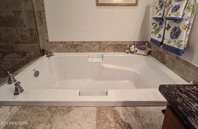 bathroom featuring vanity and a washtub