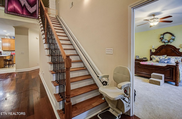 stairs featuring ceiling fan and wood-type flooring