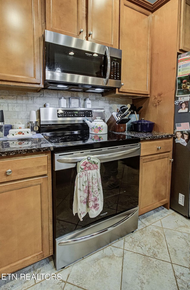 kitchen featuring dark stone countertops, appliances with stainless steel finishes, and tasteful backsplash