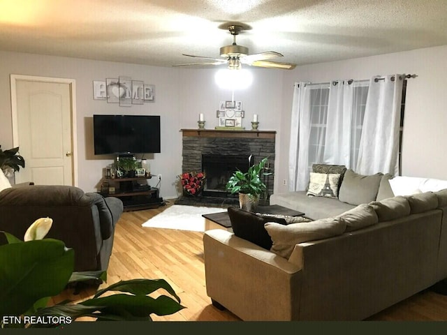 living room featuring a fireplace, a textured ceiling, hardwood / wood-style floors, and ceiling fan