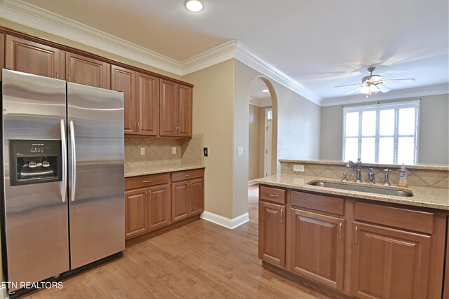 kitchen featuring light wood-type flooring, light stone countertops, sink, ceiling fan, and stainless steel fridge with ice dispenser