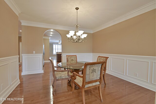 dining area featuring light wood-type flooring, crown molding, and a notable chandelier