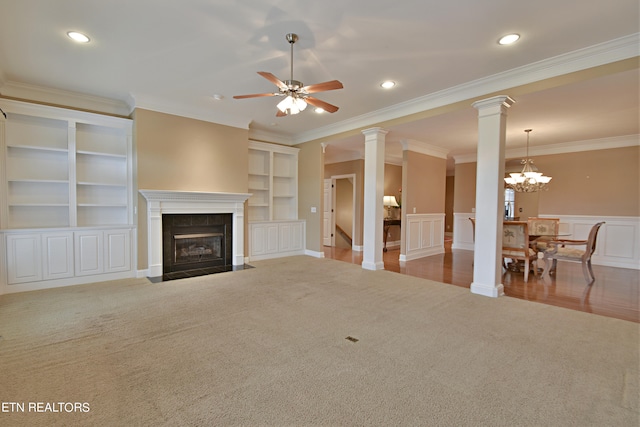 living room featuring a tile fireplace, hardwood / wood-style flooring, ceiling fan with notable chandelier, decorative columns, and ornamental molding