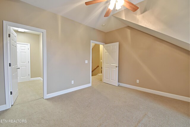 unfurnished bedroom with ceiling fan, light colored carpet, and vaulted ceiling