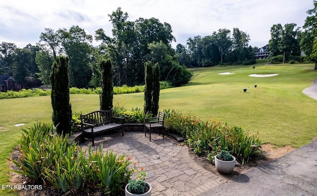 view of property's community featuring a lawn and a patio area