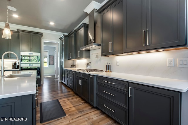 kitchen with wall chimney range hood, hanging light fixtures, stainless steel gas cooktop, and dark hardwood / wood-style flooring