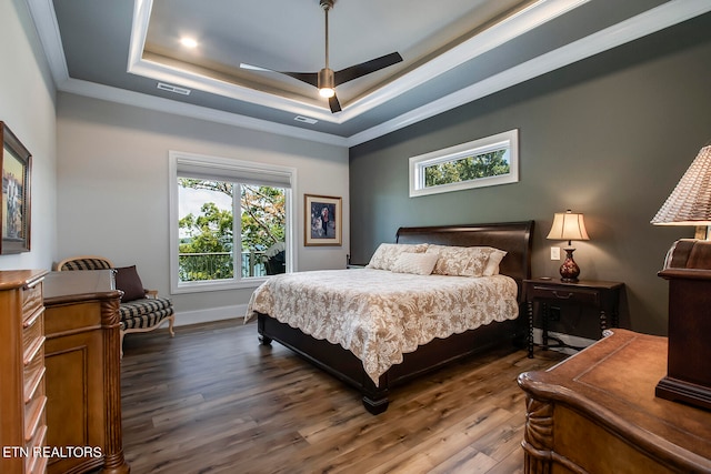 bedroom with a tray ceiling, crown molding, ceiling fan, and dark hardwood / wood-style floors