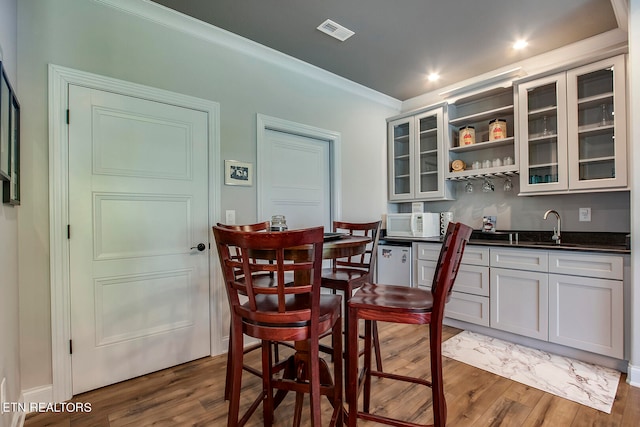 dining area featuring indoor wet bar, dark hardwood / wood-style flooring, and ornamental molding