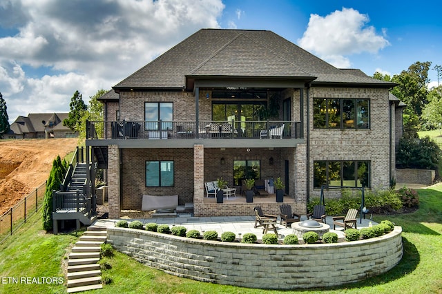 back of property with an outdoor living space with a fire pit, a patio, and a balcony