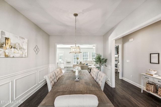 dining space featuring ceiling fan with notable chandelier and dark wood-type flooring