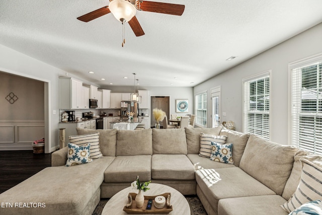 living room featuring ceiling fan, dark hardwood / wood-style flooring, and a textured ceiling