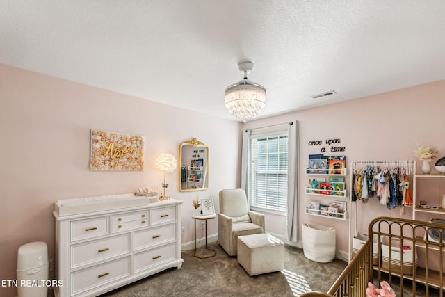 carpeted bedroom with an inviting chandelier, a textured ceiling, and a nursery area