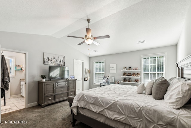 bedroom featuring lofted ceiling, light carpet, ceiling fan, a textured ceiling, and connected bathroom