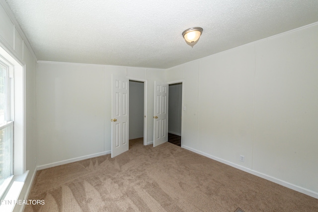 unfurnished bedroom with a textured ceiling, carpet flooring, and a decorative wall