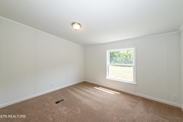 carpeted empty room with visible vents and crown molding