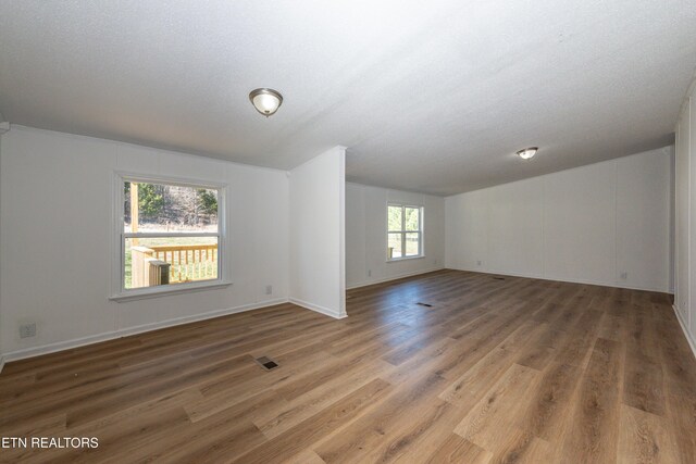 empty room featuring wood finished floors, visible vents, and a textured ceiling