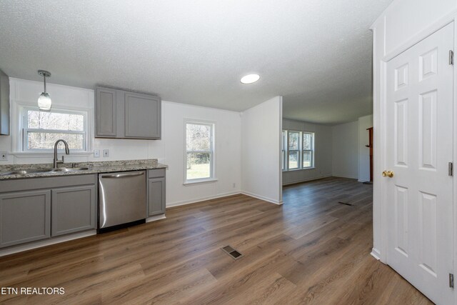 kitchen featuring visible vents, gray cabinetry, a sink, stainless steel dishwasher, and wood finished floors