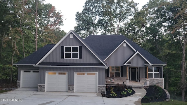 craftsman inspired home with board and batten siding, concrete driveway, an attached garage, and stone siding