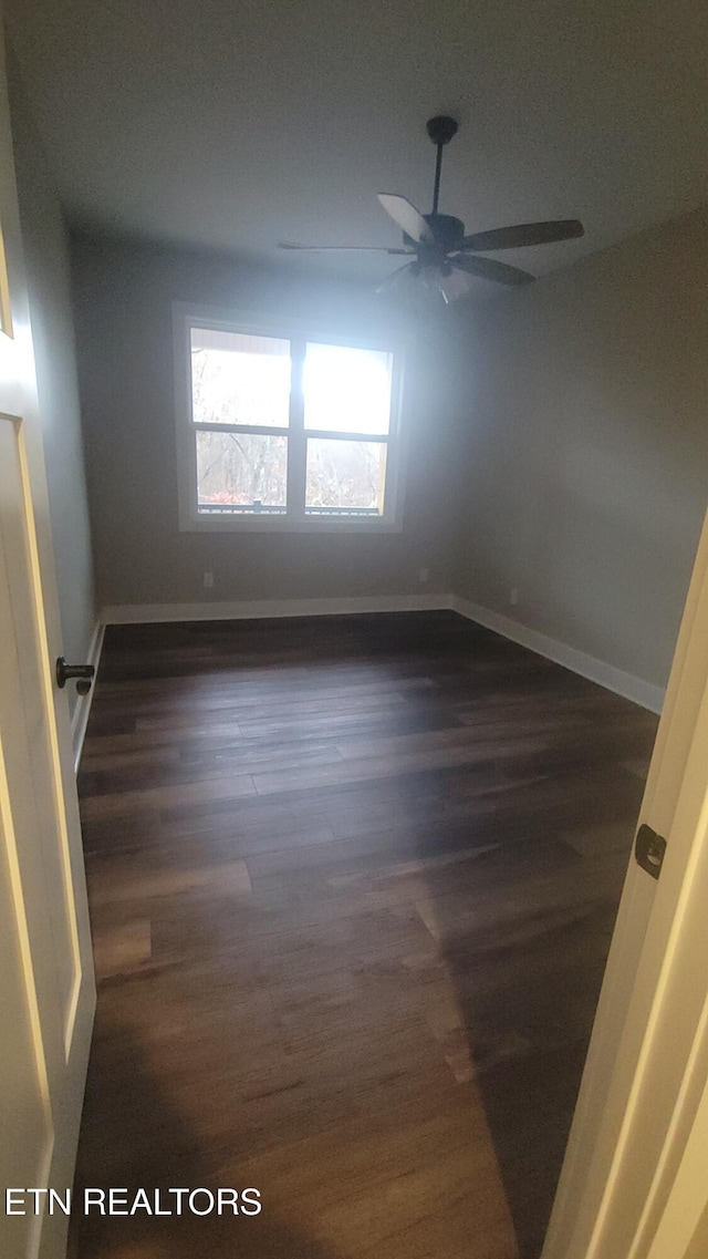 unfurnished room featuring ceiling fan and dark wood-type flooring