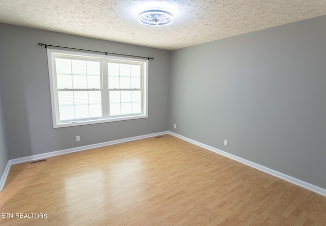 empty room featuring light wood-type flooring and a textured ceiling