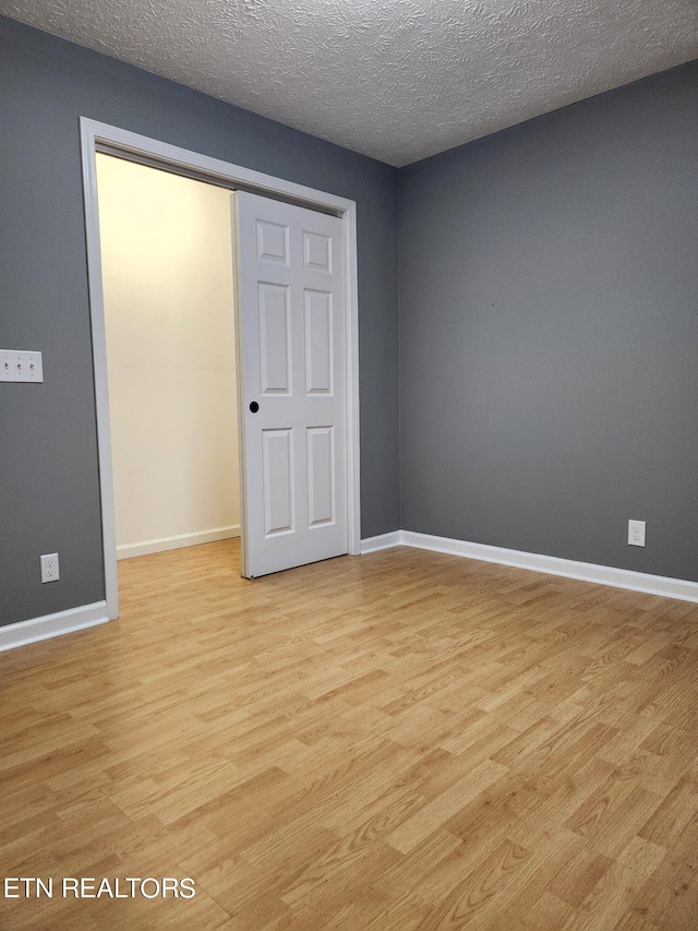 unfurnished bedroom featuring a closet, a textured ceiling, and light hardwood / wood-style flooring