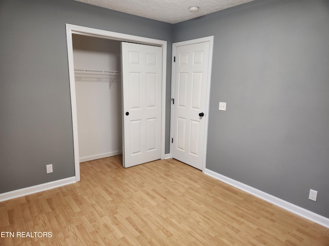 unfurnished bedroom with a textured ceiling, light hardwood / wood-style flooring, and a closet