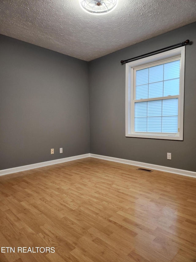 unfurnished room featuring light hardwood / wood-style floors and a textured ceiling