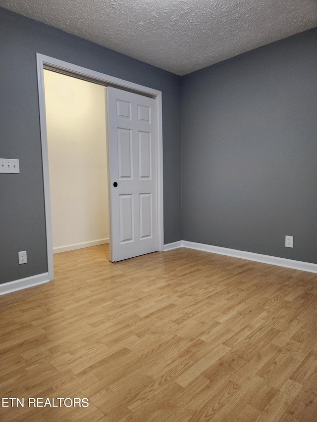 unfurnished bedroom featuring a closet, light hardwood / wood-style flooring, and a textured ceiling