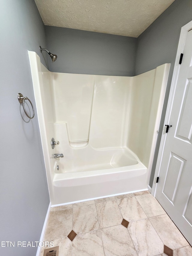 bathroom featuring tile patterned floors, shower / bathing tub combination, and a textured ceiling