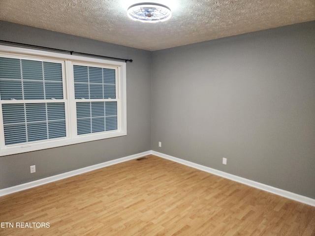 spare room featuring hardwood / wood-style floors and a textured ceiling