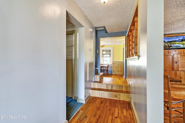 hall featuring a textured ceiling and wood-type flooring