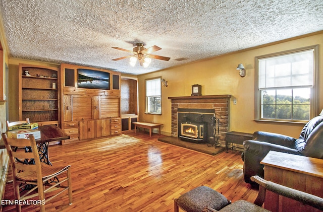 living room with a textured ceiling, ceiling fan, hardwood / wood-style flooring, and a fireplace