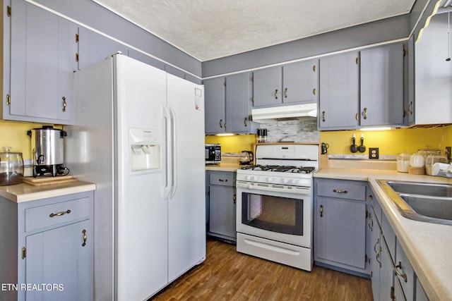 kitchen with a textured ceiling, dark hardwood / wood-style floors, white appliances, sink, and gray cabinets