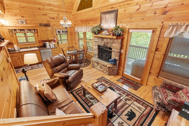 living room with light hardwood / wood-style flooring, a notable chandelier, a stone fireplace, and wooden walls