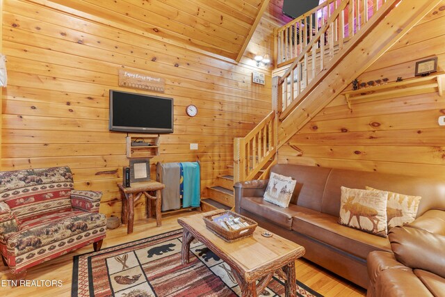 living room featuring lofted ceiling, hardwood / wood-style floors, and wooden walls