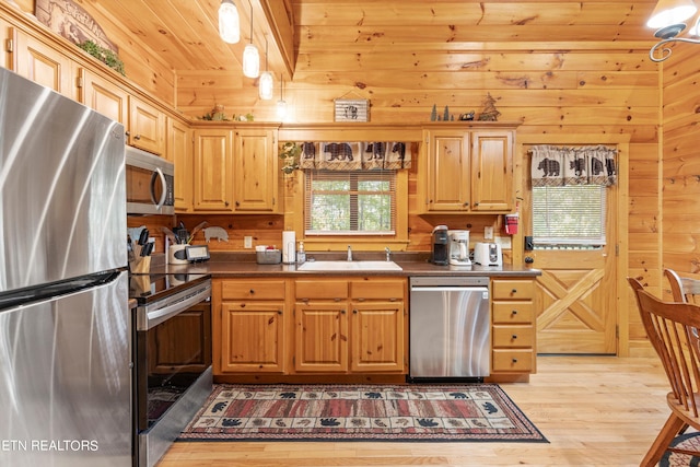 kitchen with wooden walls, wooden ceiling, light hardwood / wood-style flooring, appliances with stainless steel finishes, and sink