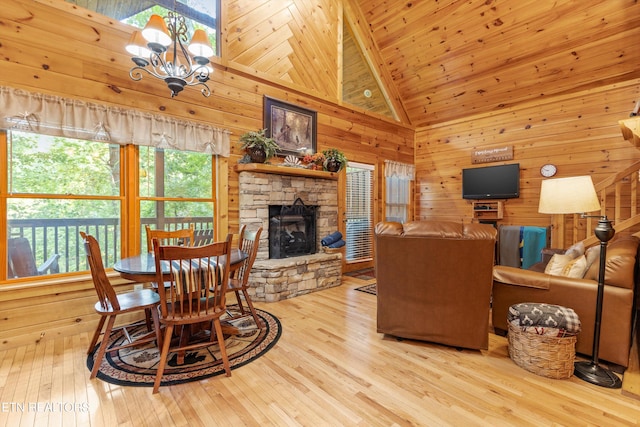 living room with high vaulted ceiling, light hardwood / wood-style flooring, a chandelier, and a stone fireplace