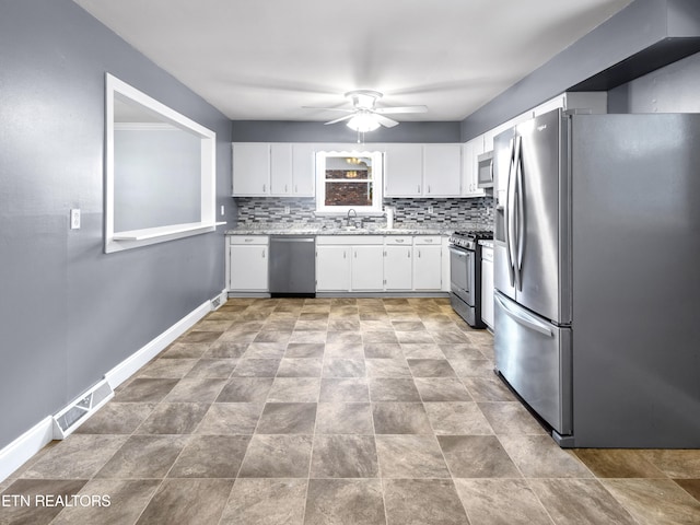 kitchen featuring decorative backsplash, appliances with stainless steel finishes, ceiling fan, sink, and white cabinetry