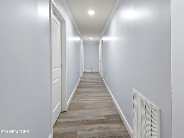 corridor featuring light wood-type flooring and crown molding