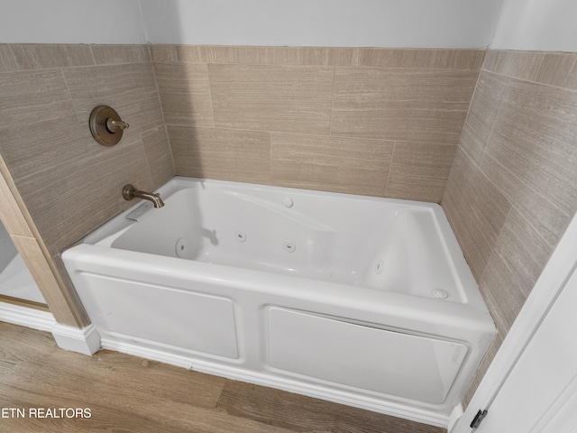 bathroom featuring hardwood / wood-style floors and tiled tub