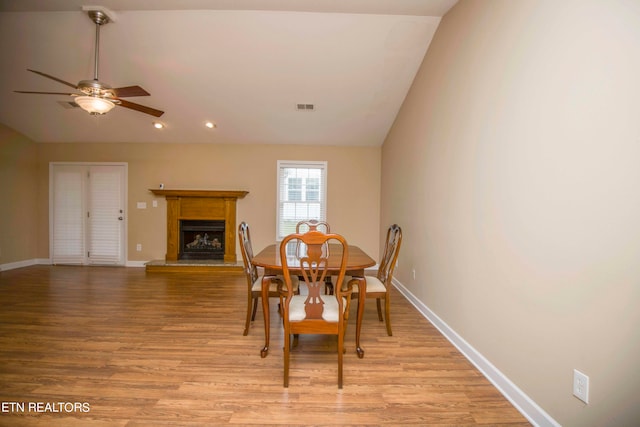 dining space with ceiling fan, vaulted ceiling, and light hardwood / wood-style flooring