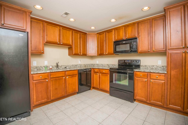 kitchen with black appliances, light stone counters, and light tile patterned flooring