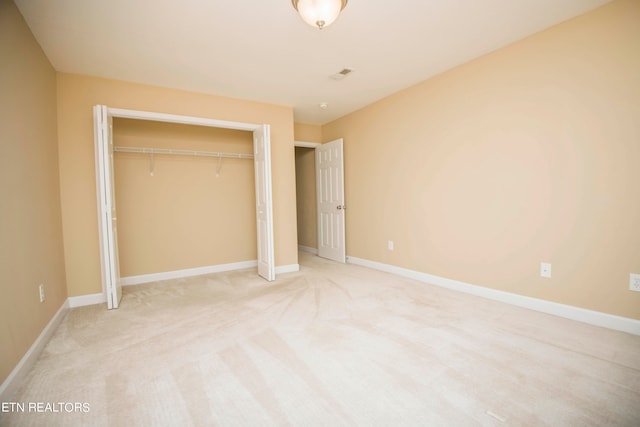 unfurnished bedroom featuring a closet and light colored carpet