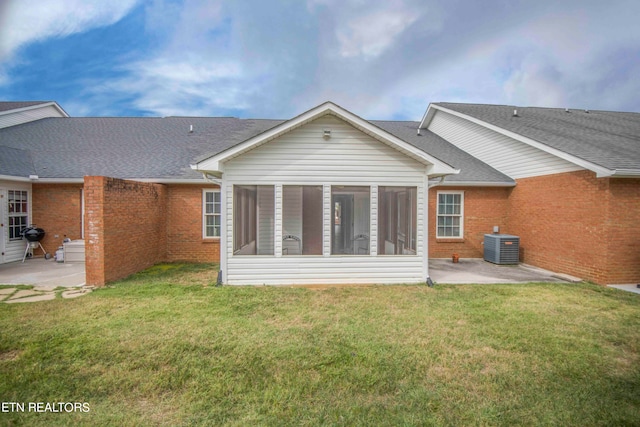 rear view of property with a sunroom, a yard, a patio, and central AC unit