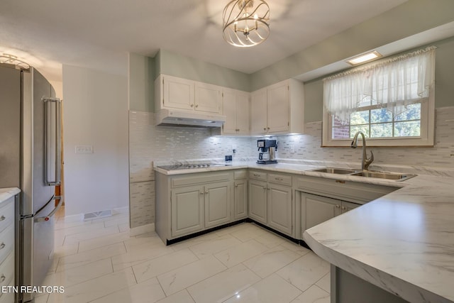 kitchen featuring under cabinet range hood, marble finish floor, a sink, and freestanding refrigerator