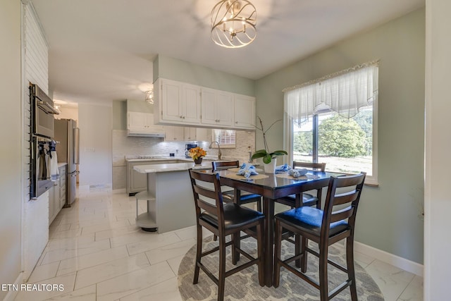 dining space featuring a notable chandelier, marble finish floor, and baseboards