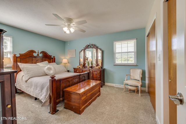 bedroom with a closet, visible vents, light carpet, ceiling fan, and baseboards