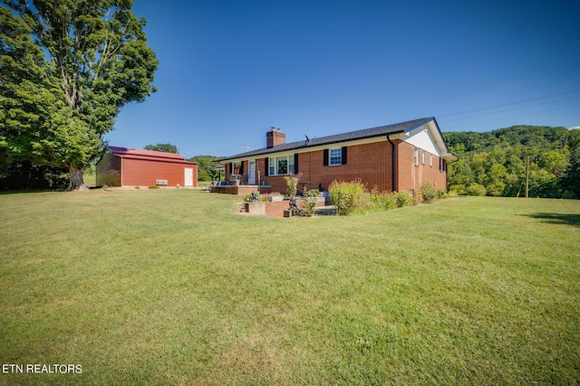 back of house featuring brick siding, a chimney, and a lawn