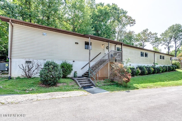 manufactured / mobile home with stairway and a front lawn