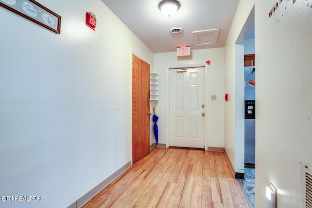 hallway with baseboards, visible vents, and light wood-type flooring